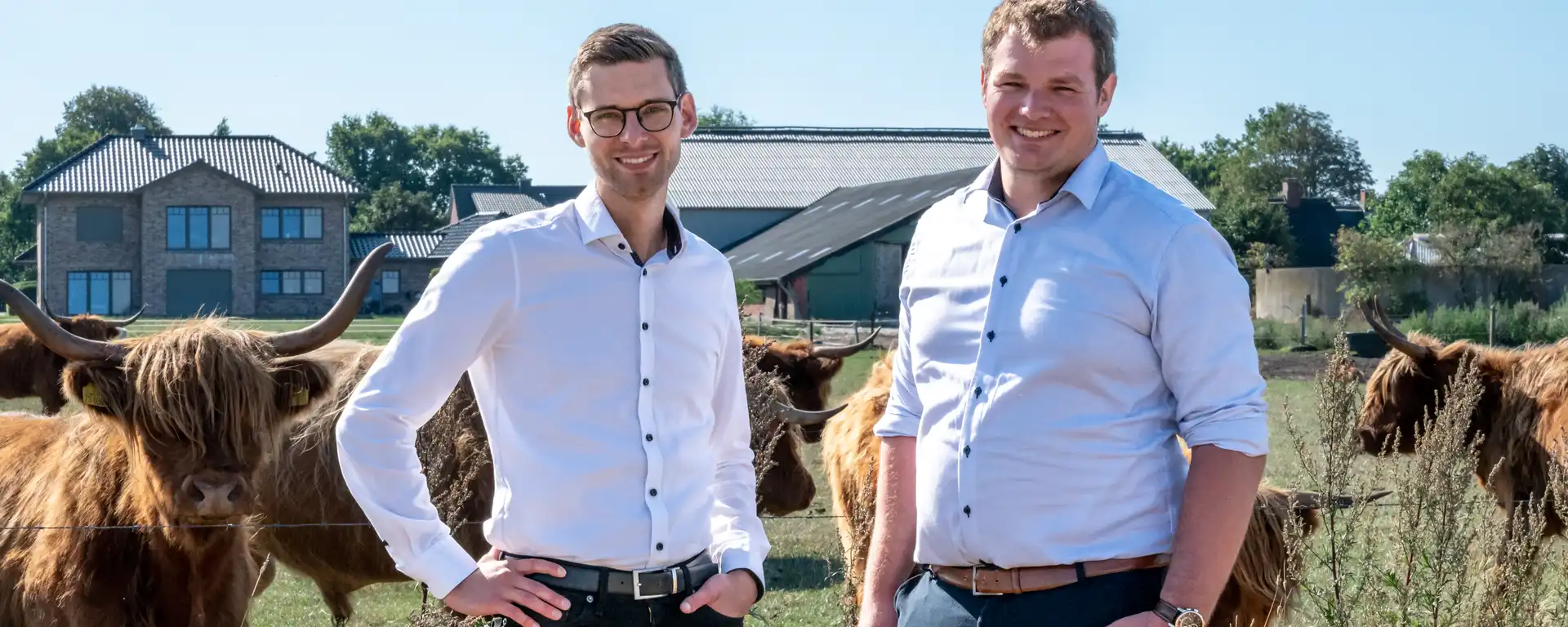 Zwei wetreu Mitarbeitende vor Kühen auf einer Weide